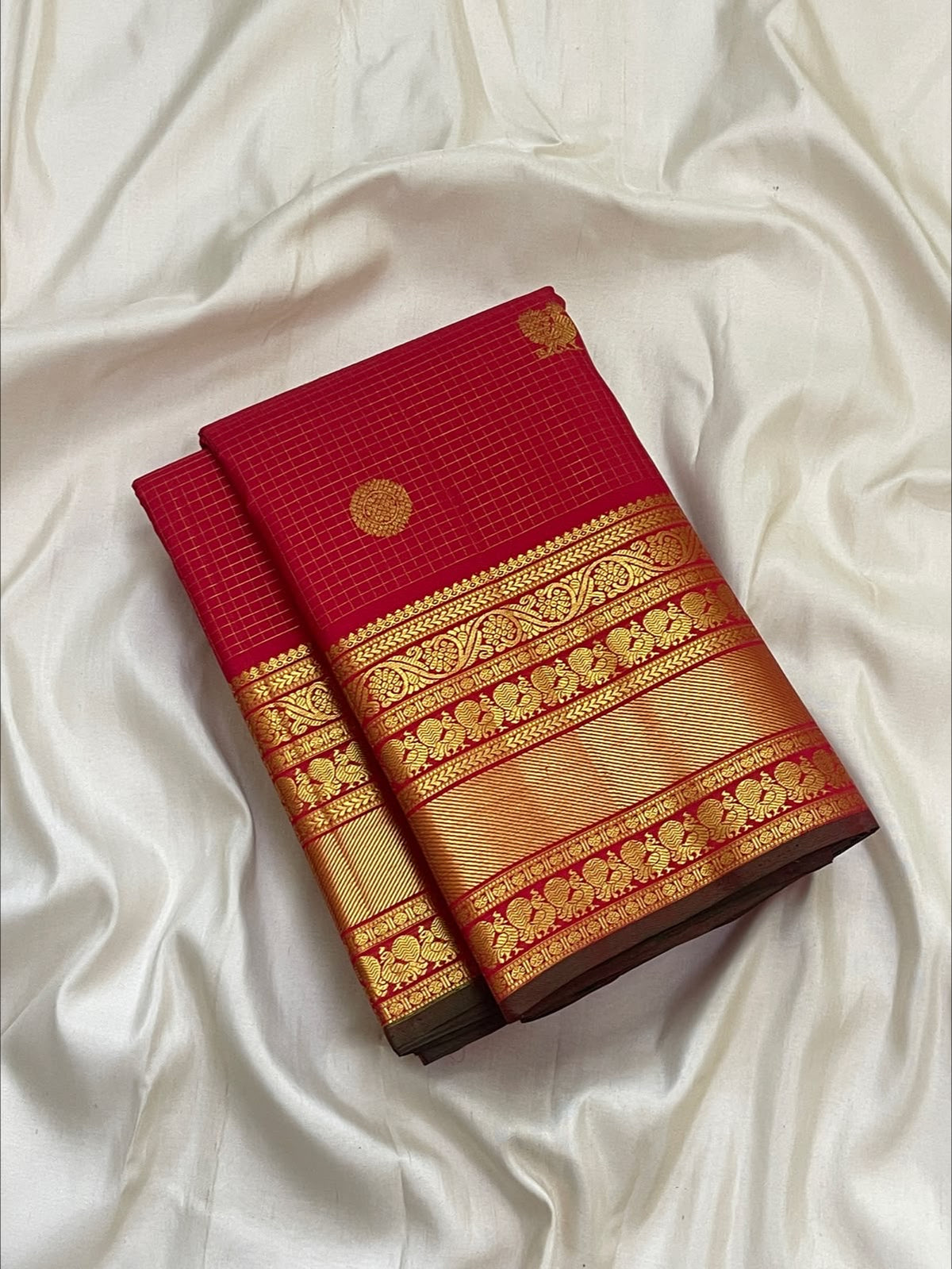 Stacked traditional Kanchipuram border in layered gold zari bands on a kumkum red silk saree