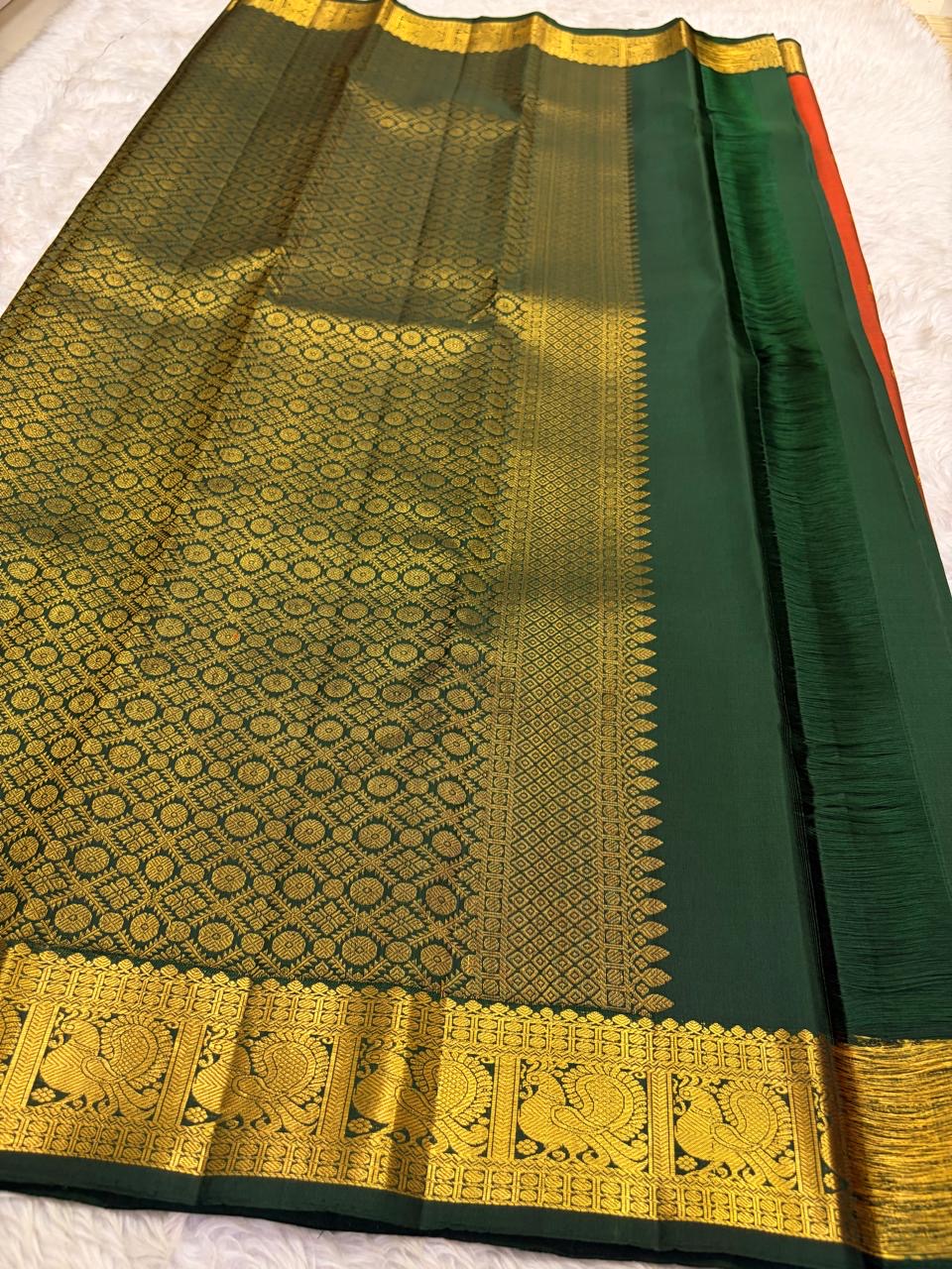 Deep forest green pallu with large gold zari peacock motifs on rust orange Kanchipuram silk saree — Idam Living