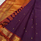 Close view of aubergine-purple silk meeting a warm rust-red ornamental classic-gold zari border.
