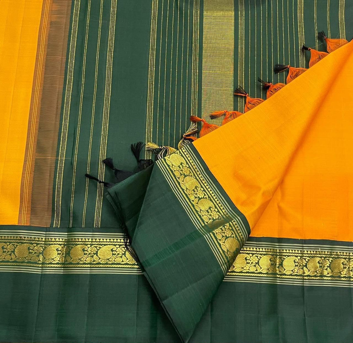 Deep green Kaal Irangiya border with gold zari bird and floral-vine detailing on saffron silk saree