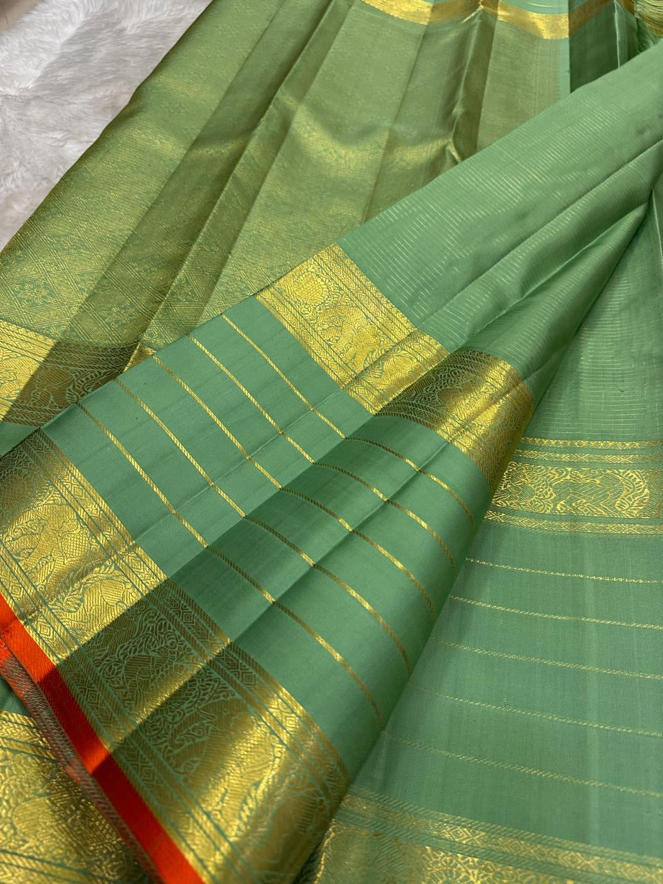 Muted green Kanchipuram silk saree with small spaced antique-gold zari buttas.