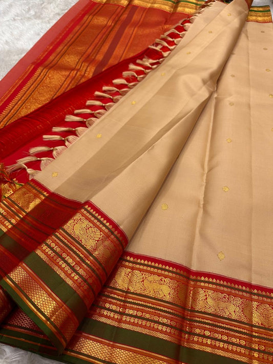 Close-up of sandal beige silk body with scattered gold zari butta motifs — coin and geometric forms