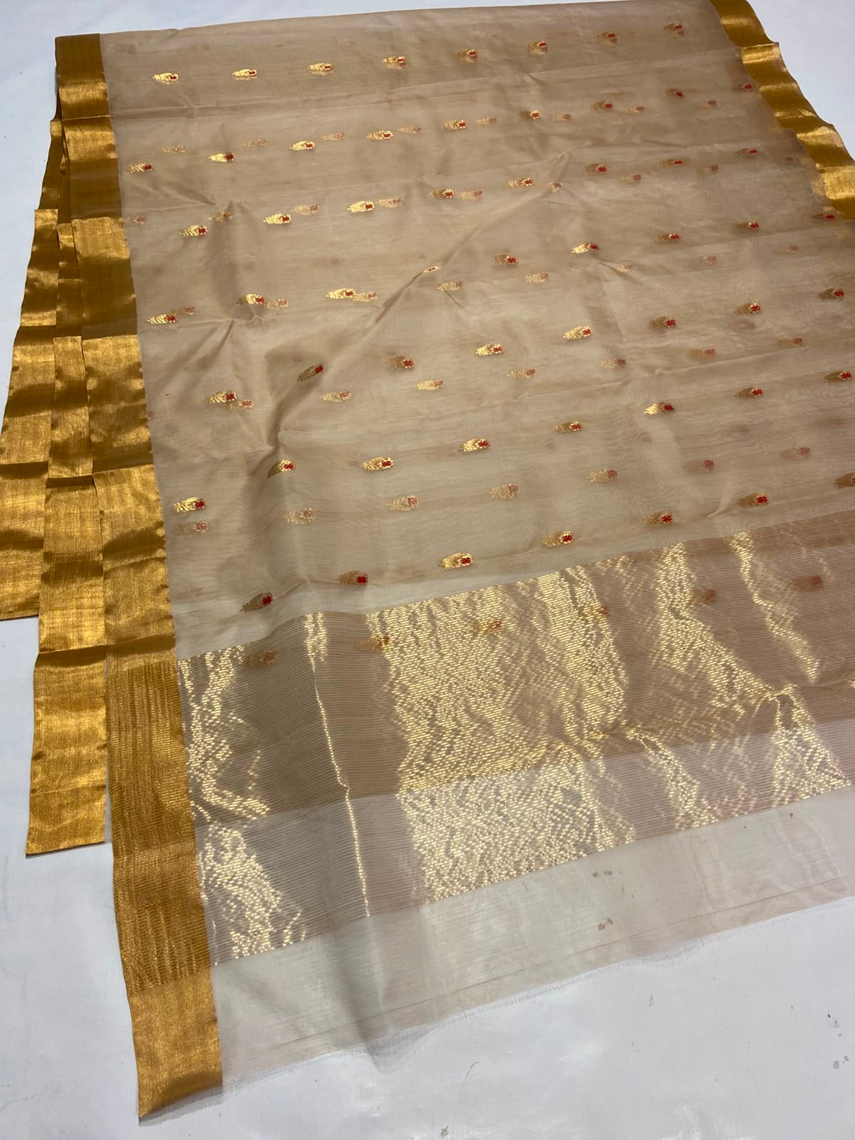 Sandalwood Beige Katan Silk Chanderi saree laid flat showing petite gold buttas and clean gold border.