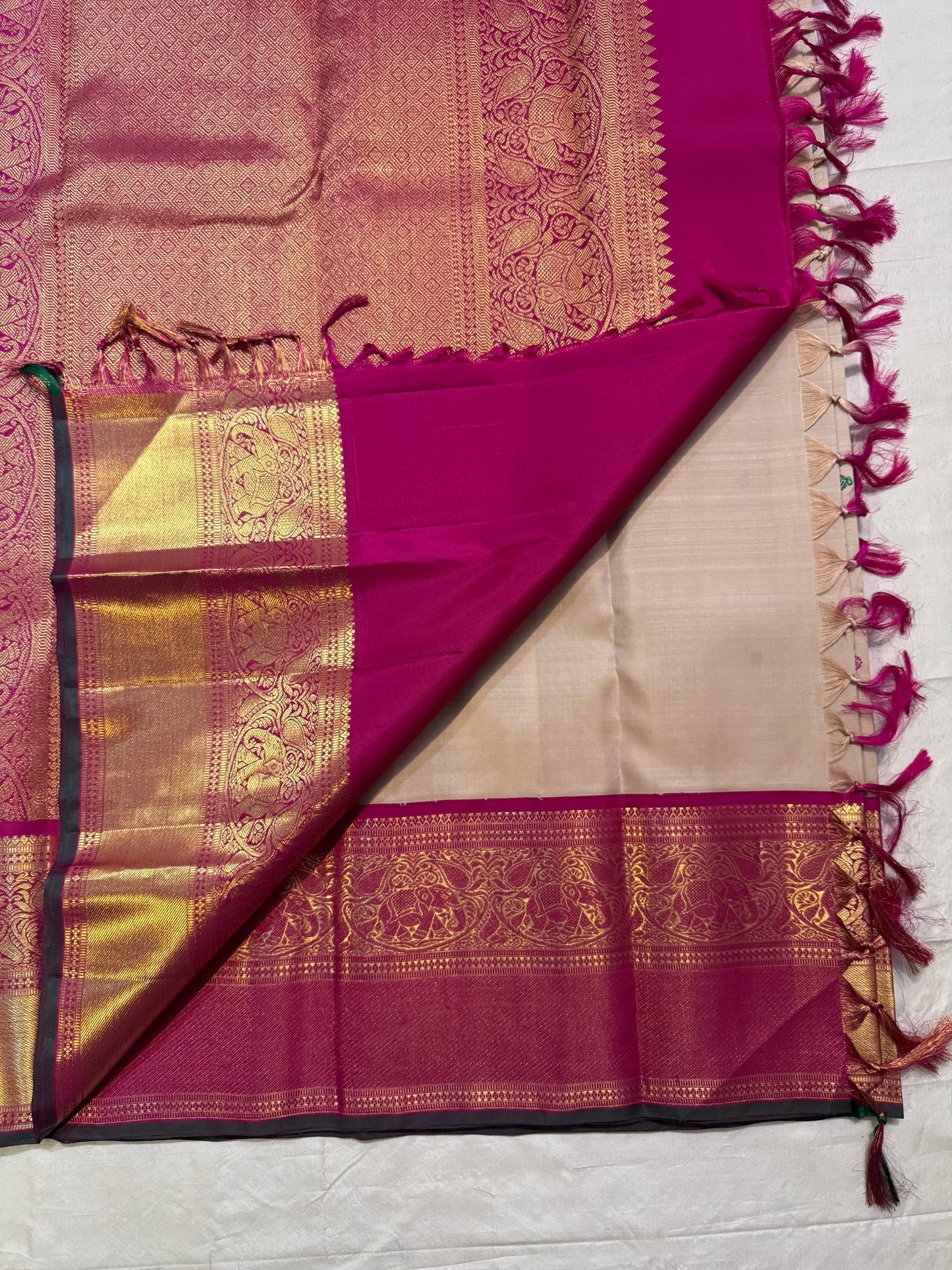 Folded view of a Sandalwood Beige and Deep Magenta Pure Silk Korvai Kanchipuram saree with alternating pink and green silk-thread buttas and golden paisley motifs