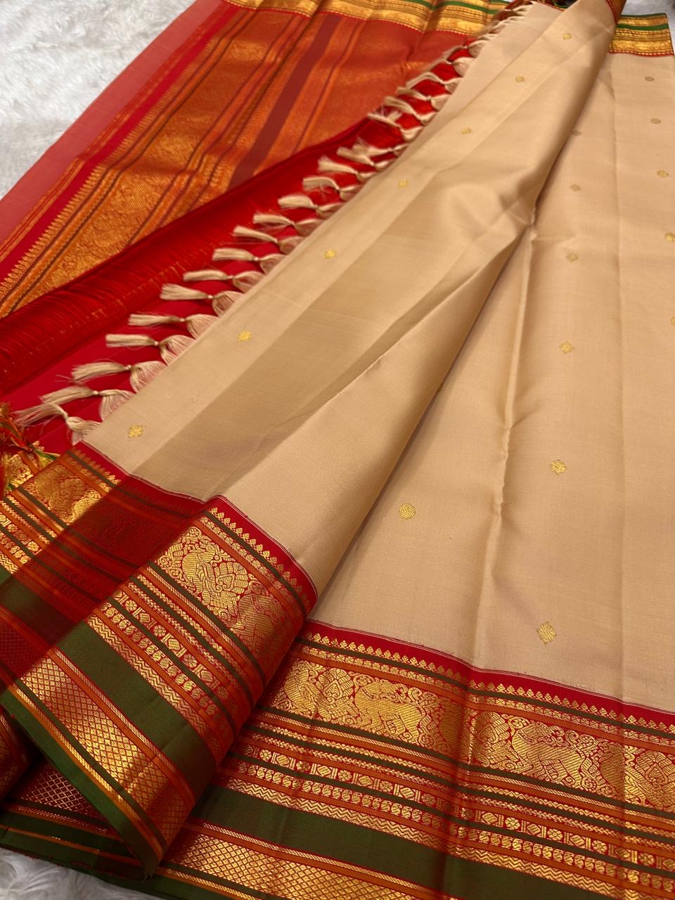 Close-up of red and green korvai border with gold zari temple motifs on sandstone beige Kanchipuram saree — Idam Living