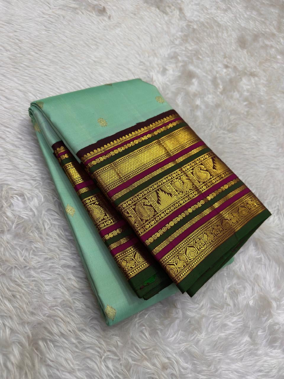 Seafoam green Kanchi Pattu saree folded to show contrast deep green and magenta Varisaipet border