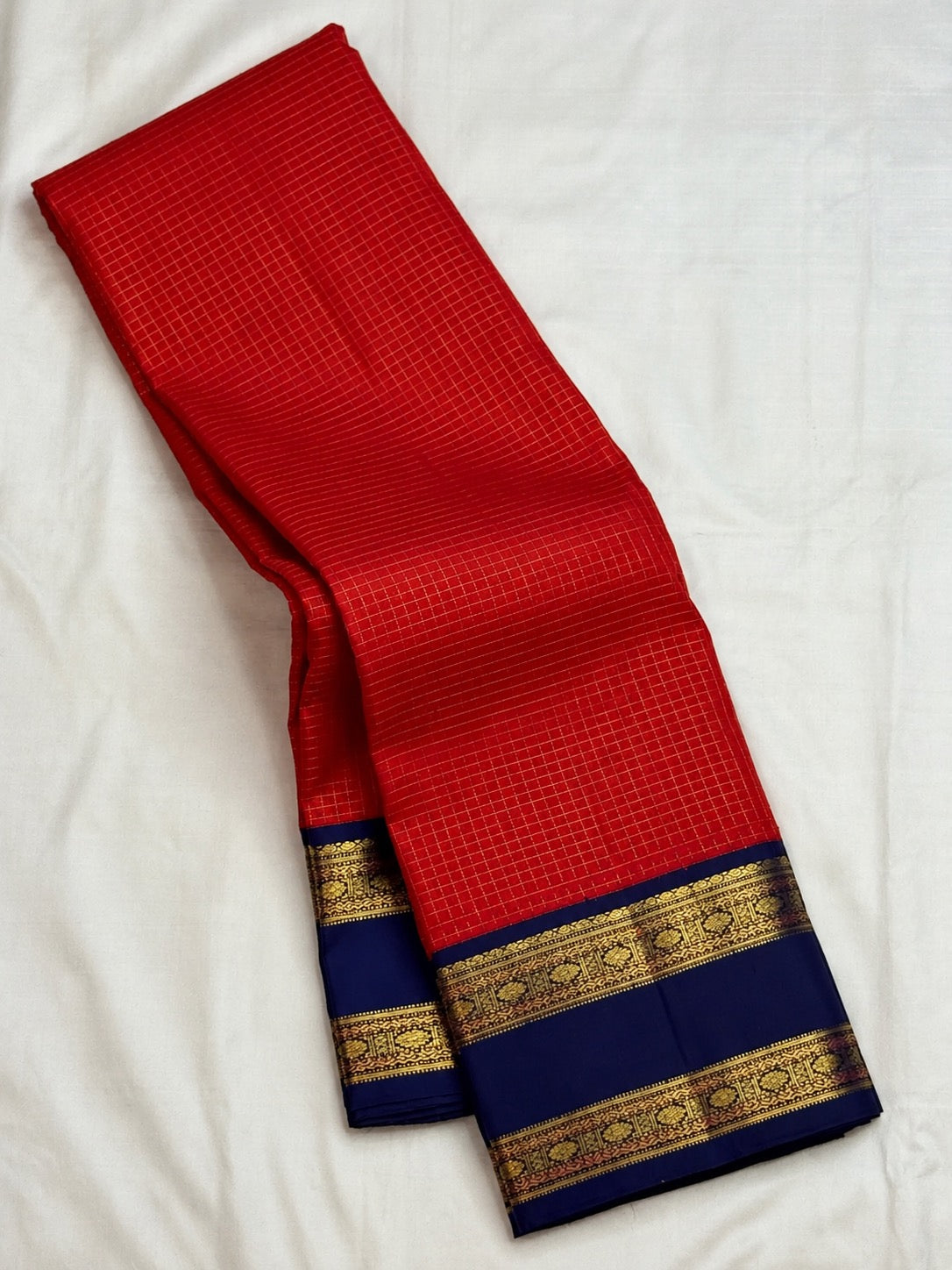 Deep vibrant red handwoven Kanchipuram silk saree with neelam-blue border and pallu.