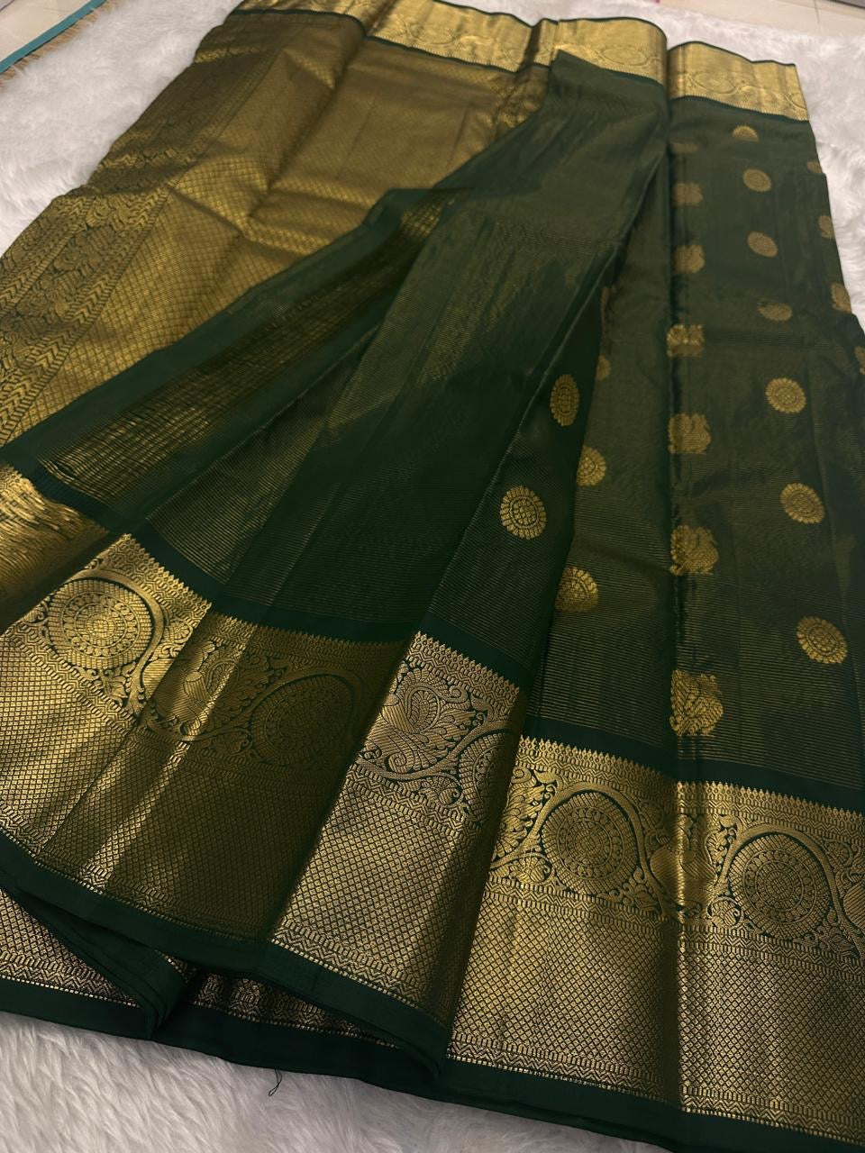 Full view of deep maragatham green with a soft petal pink pallu Kanchipuram saree showing airy butta placement across the body.