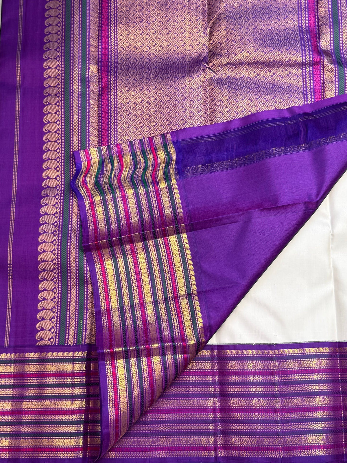 Silk-thread Mayil Chakram motifs on an ivory white Kanchipuram Varisaipet saree.