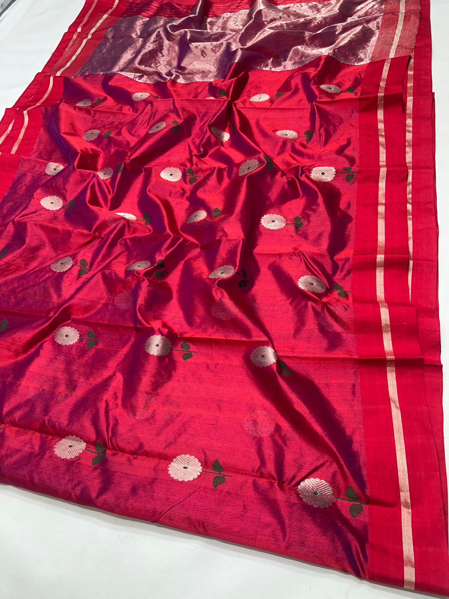 Close-up of silver floral buttas with green stems and leaves on Raspberry Red Pattu Silk Chanderi saree