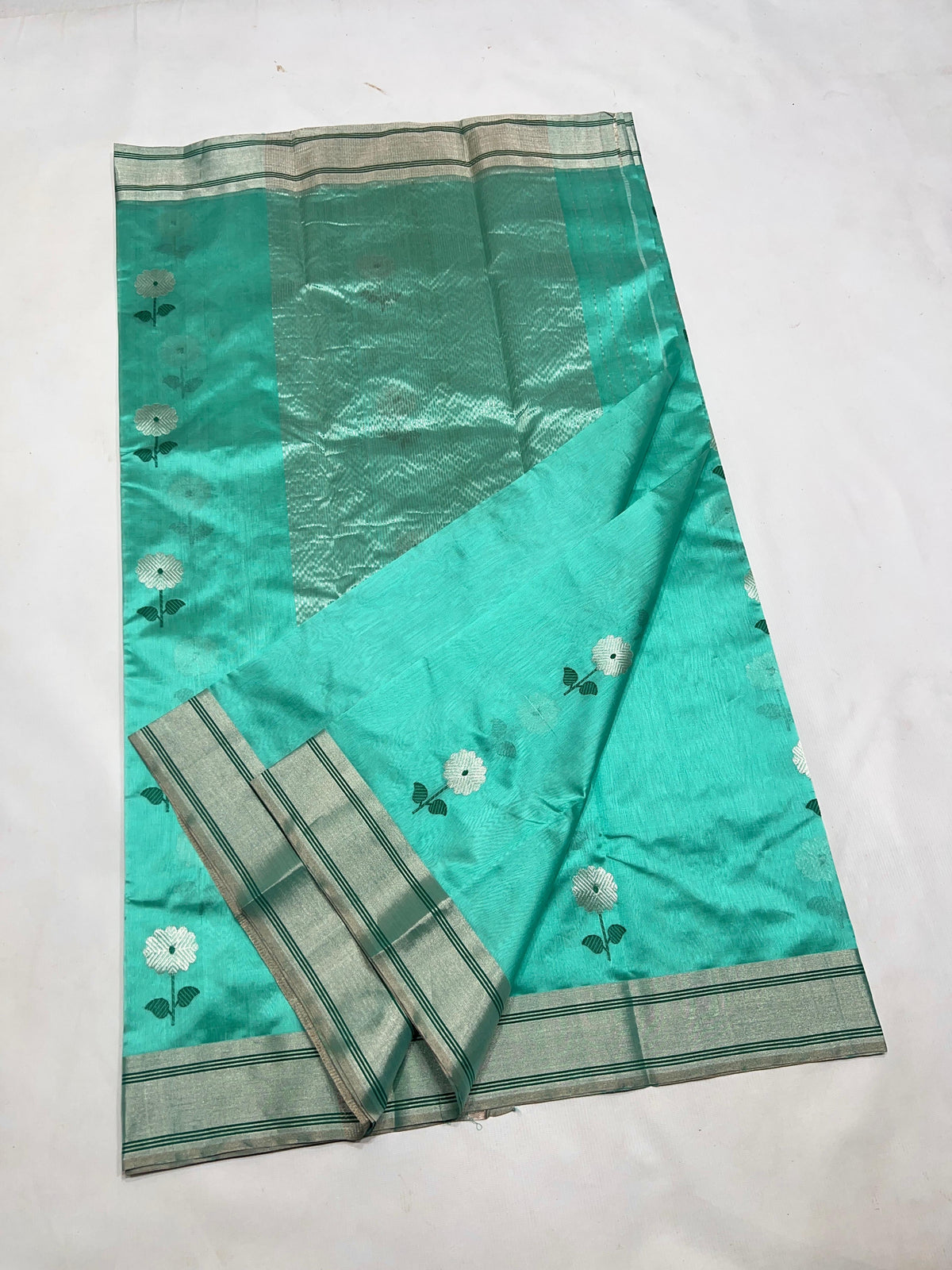 Silver floral buttas with deep green stems and leaves on an Aqua Turquoise Pattu Silk Chanderi saree