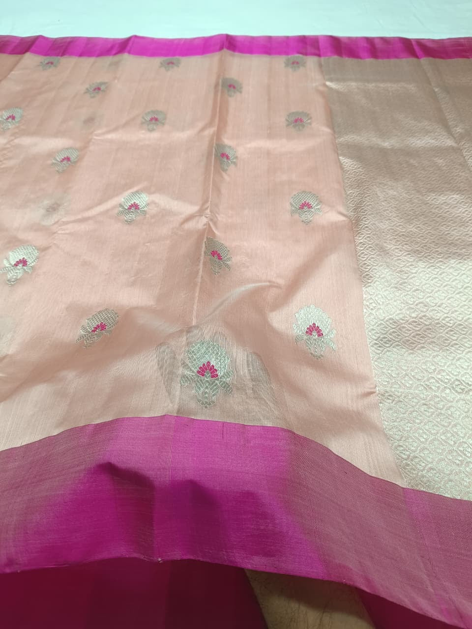 Detail of silver floral buttas with Rani Pink woven accents on a Blush Peach Chanderi silk saree