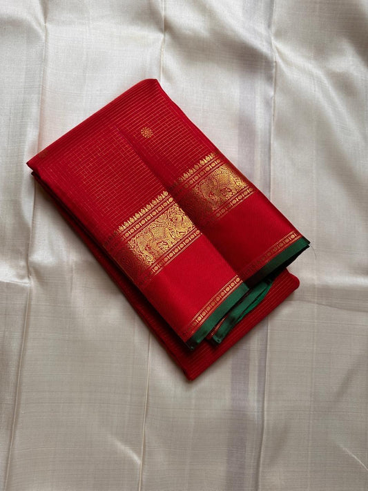Full view of glowing red Kanjipuram silk showing fine zari grid, small buttas and traditional border
