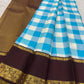 Folded sky blue and ivory checked silk beside kaapi brown Vanasringaram border with gold-toned zari