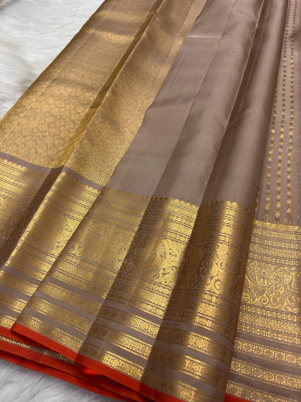 Smoky Taupe pure silk Kanchipuram Butta saree with antique-gold zari border and Burnt Orange selvedge.