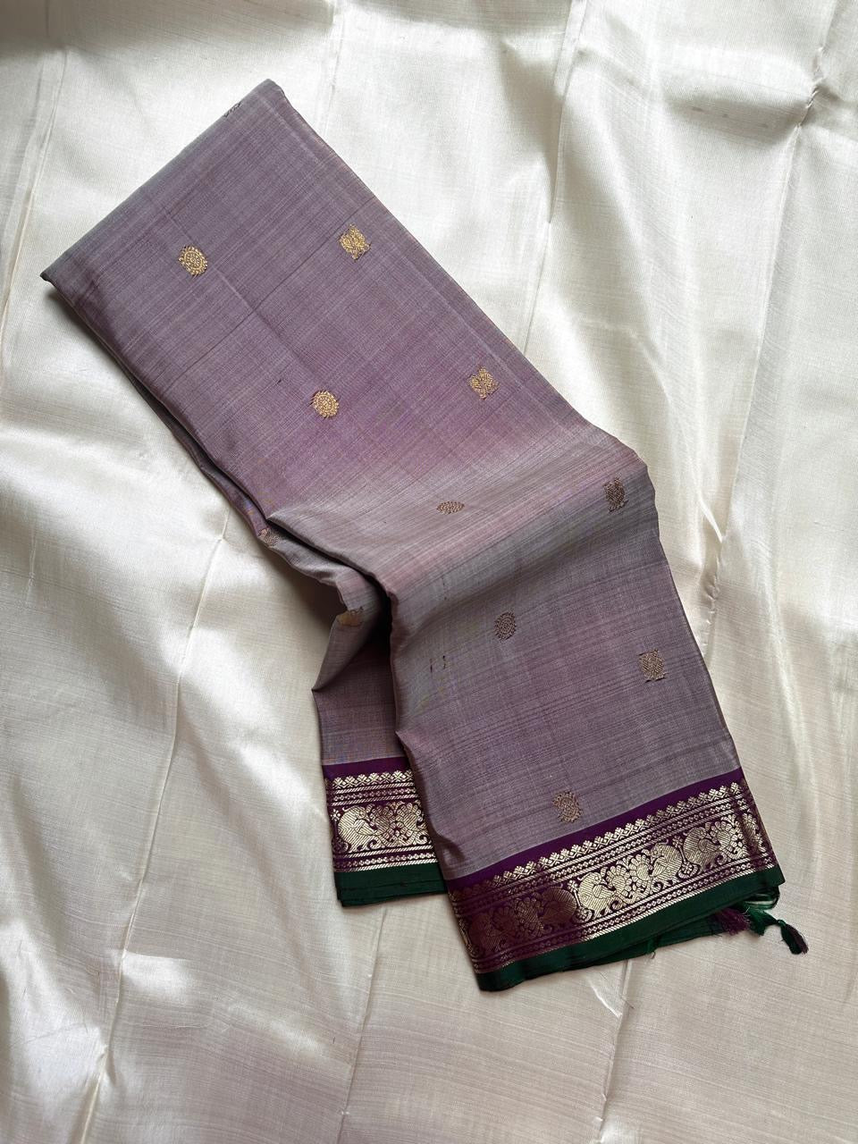 Grey pure Kanchipuram silk saree with scattered gold butti and a purple zari woven floral border with green edge.