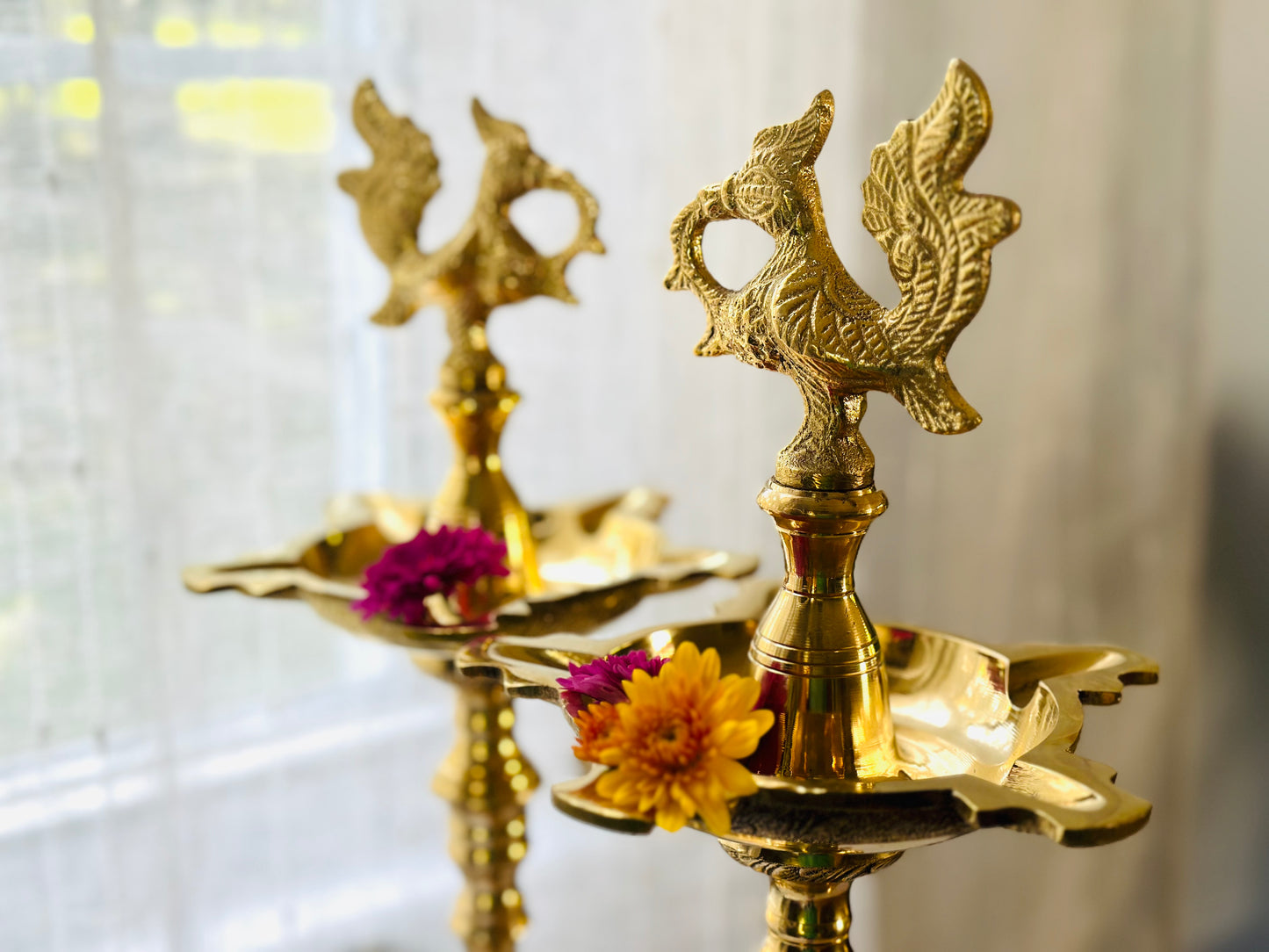 South Indian brass Kuthu Vilakku lamp pair styled with floating flowers in urli