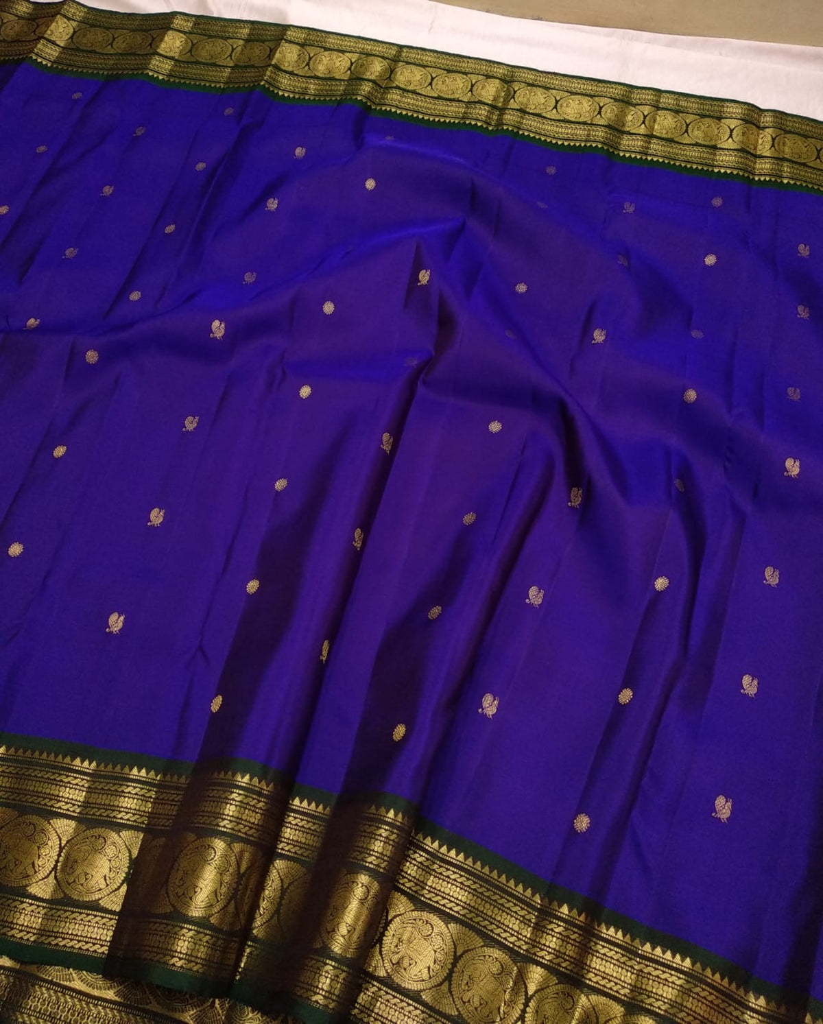 Sorgavaasal Mayil border in antique-gold zari on bottle-green silk, with Mayil motifs in circular temple-inspired frames.