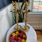 Solid brass Kuthu Vilakku oil lamps placed near window with floral brass urli bowl