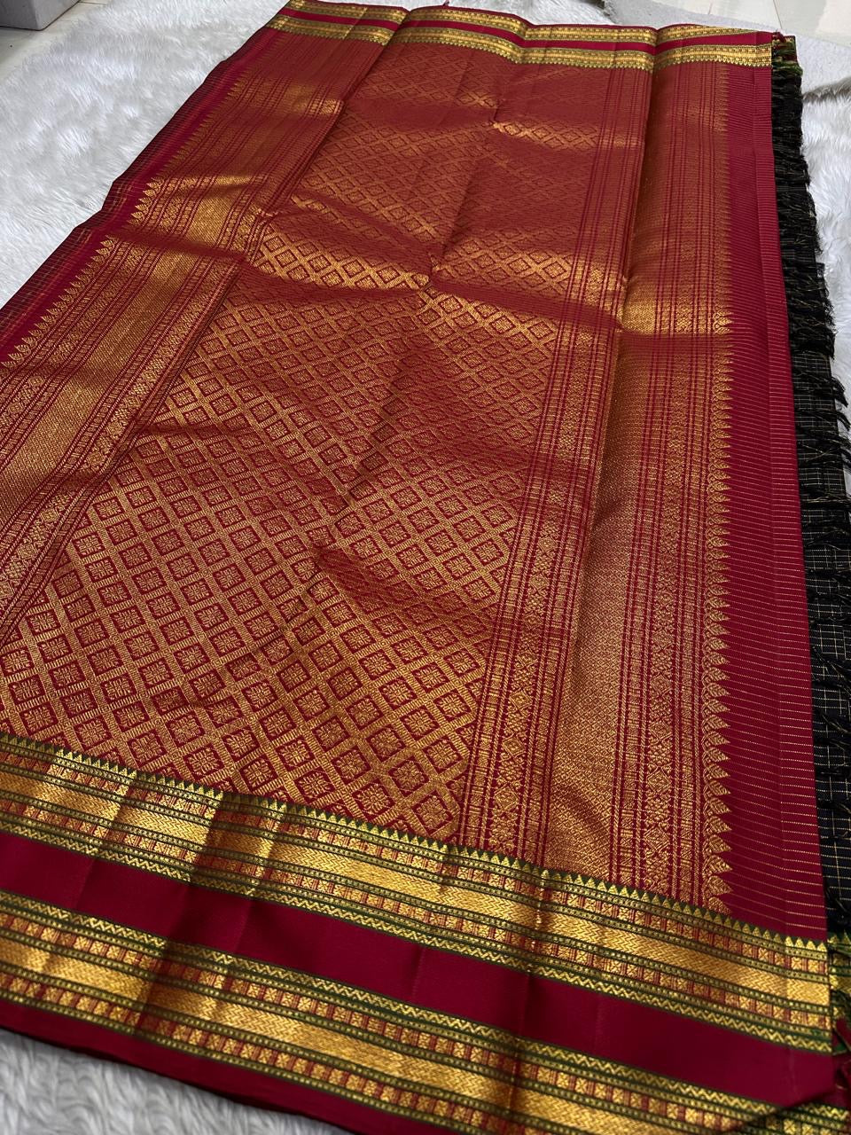 Draped view of black checked Kanchipuram silk saree with antique gold zari motifs, maroon pallu, and woven border