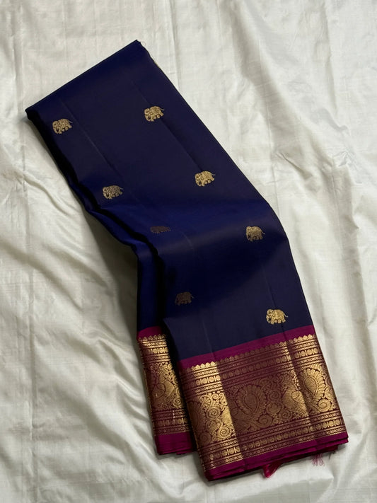 Stacked navy Pure Kanchipuram silk saree showing gold elephant buttas and an ornate zari woven border with a magenta edge.