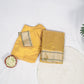 Overhead flat-lay of folded sunflower yellow Chanderi silk saree placed beside a round mat and small bowl, showing border and body color.