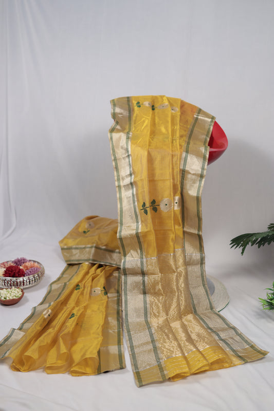 Close-up of sunflower yellow Chanderi silk saree highlighting a white floral butti, green stem detail, and gold zari border along the edge.