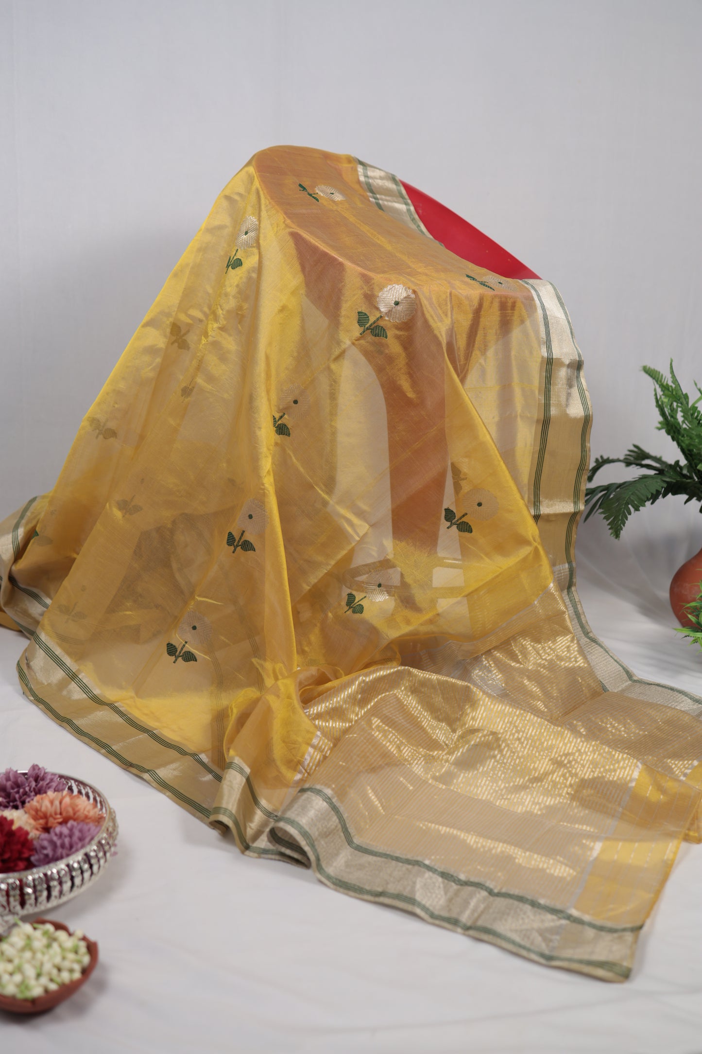 Vertical studio display of sunflower yellow Chanderi silk saree draped to show length, sheer quality, floral buttas, and gold zari border.