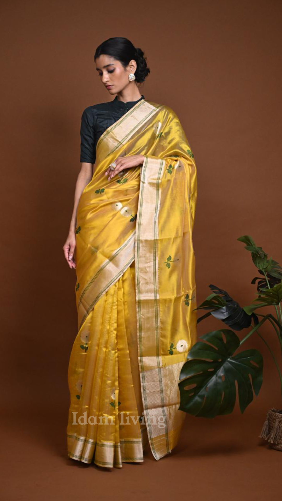 Flat-lay of folded sunflower yellow Chanderi silk saree on a white surface, showing gold zari border with fine green stripe detailing.