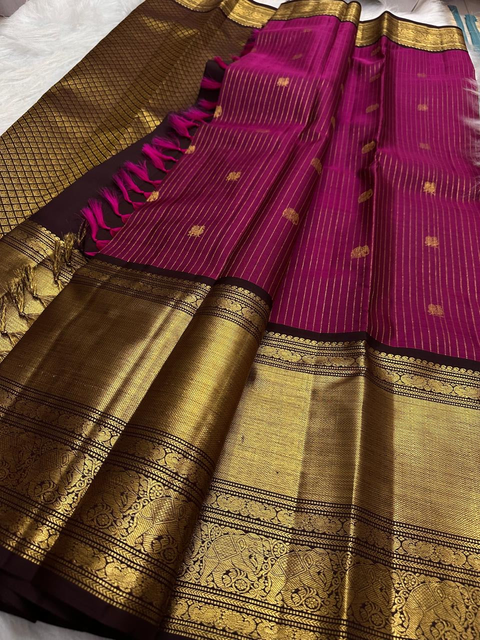 Close view of small gold buttas spaced across the vadamalli pink and antique gold silk