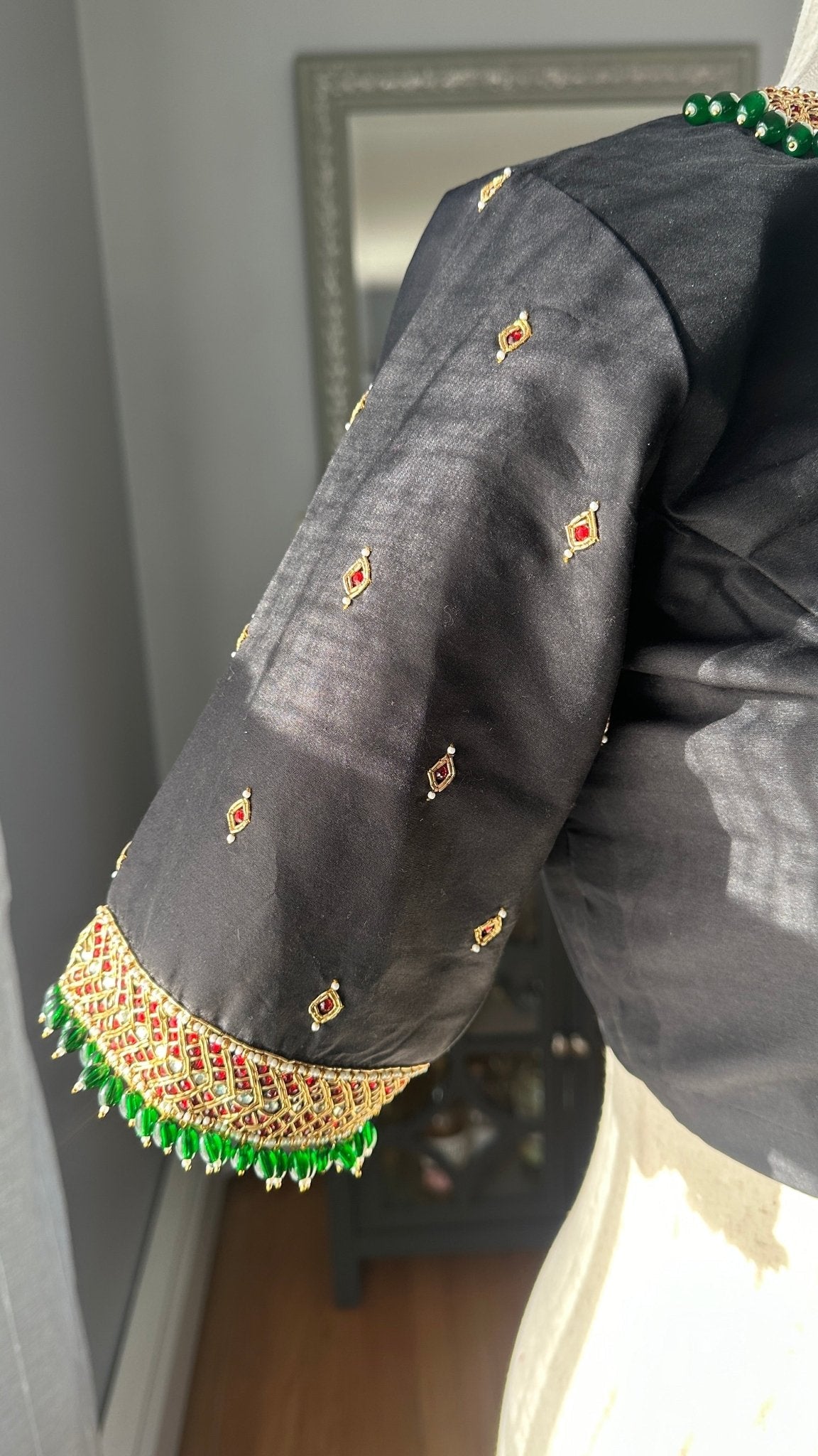 Close-up of durable kemp stones and hand embroidery on black silk cotton Tanjore blouse