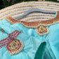 Close-up of durable kemp stones and hand embroidery on pastel green silk blouse