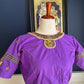 Purple silk Tanjore Treasure blouse with gold kemp embroidery photographed against a white curtain