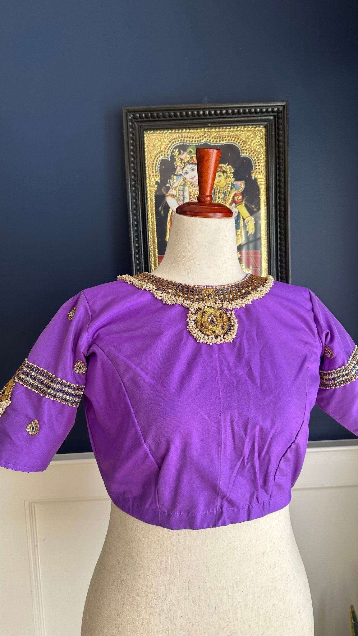 Purple silk Tanjore Treasure blouse with gold kemp embroidery photographed against a white curtain