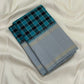 Folded teal and black checked Pure Kanchipuram silk saree with silver grey border on white backdrop