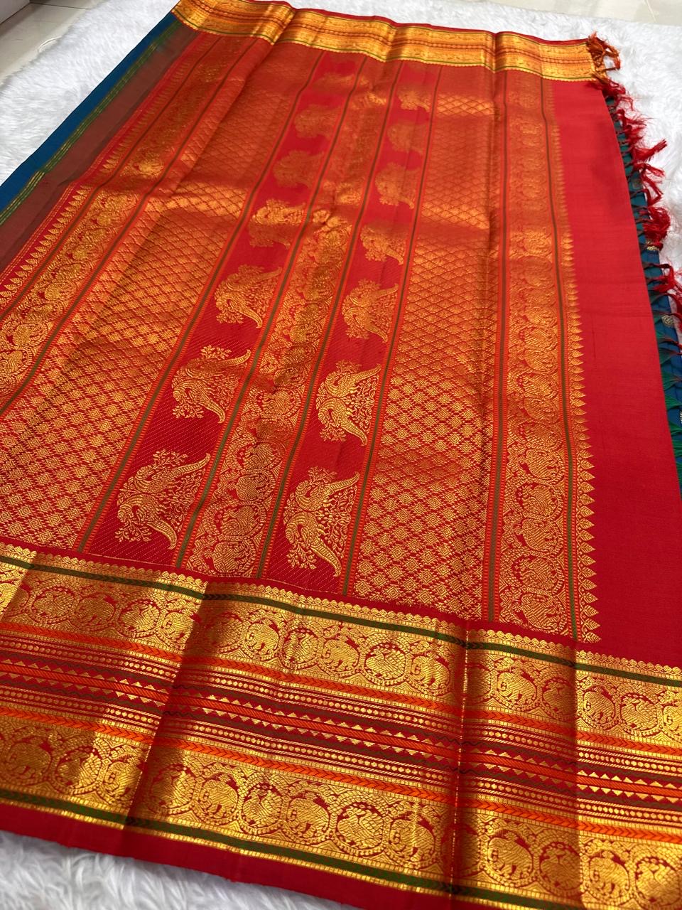 Peacock blue KanchiPattu saree folded to show Korvai body-border interlocking and red contrast
