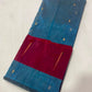 Folded Teal Blue Tissue Silk Chanderi saree with sparse gold and silver-toned woven buttas.