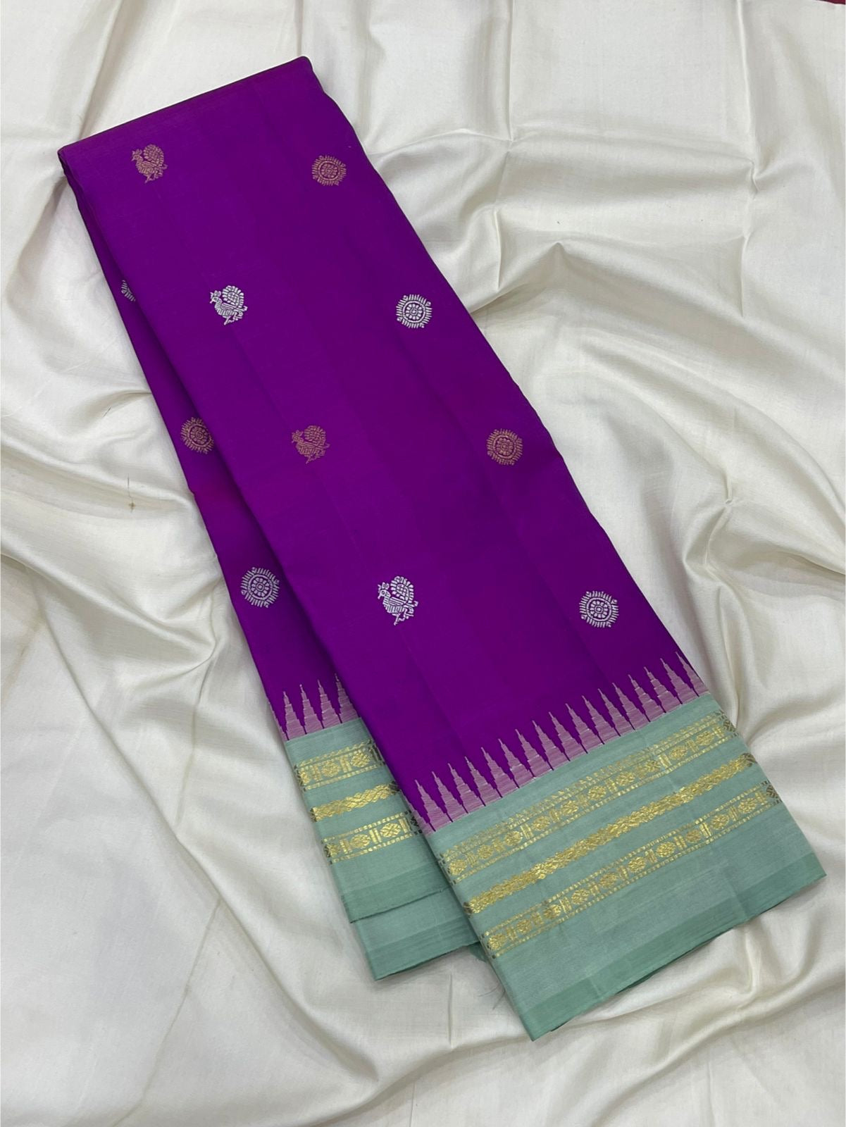 Orchid purple and ice blue Kanjipuram silk saree folded showing Mayil Chakram butta body and contrast ice blue Korvai border