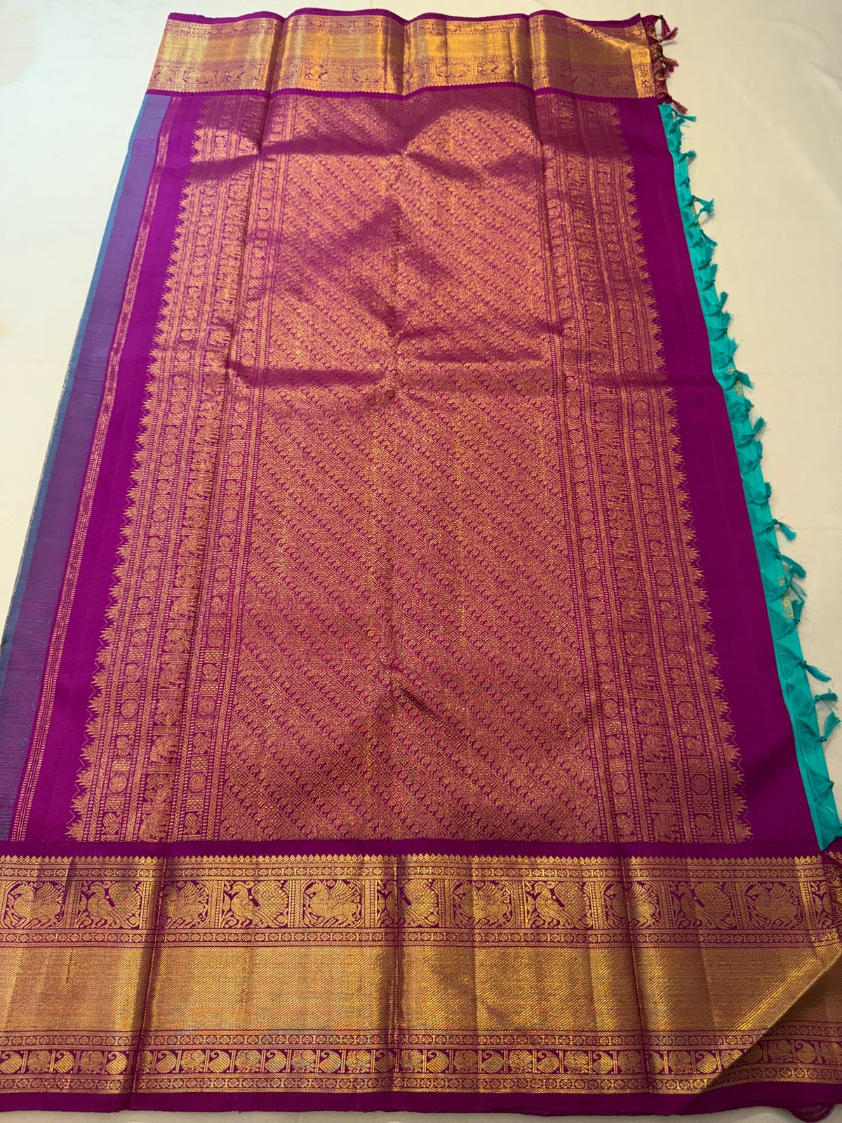 Detailed view of teal and gold zari border against the vivid magenta-pink Vairaoosi silk body