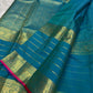 Close view of floral-vine and geometric gold-zari detailing in the teal Kanchipuram border.