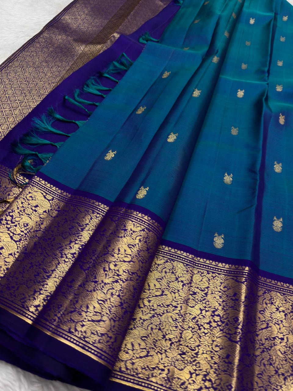 Full view of teal and royal blue pure silk Kanchipuram saree with gandaberunda butta on banana leaf — Idam Living