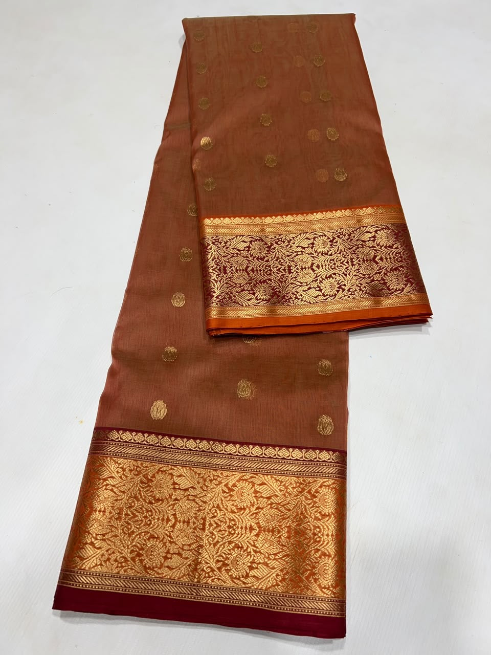 Terracotta Chanderi saree with an intricate gold floral border framed in deep maroon