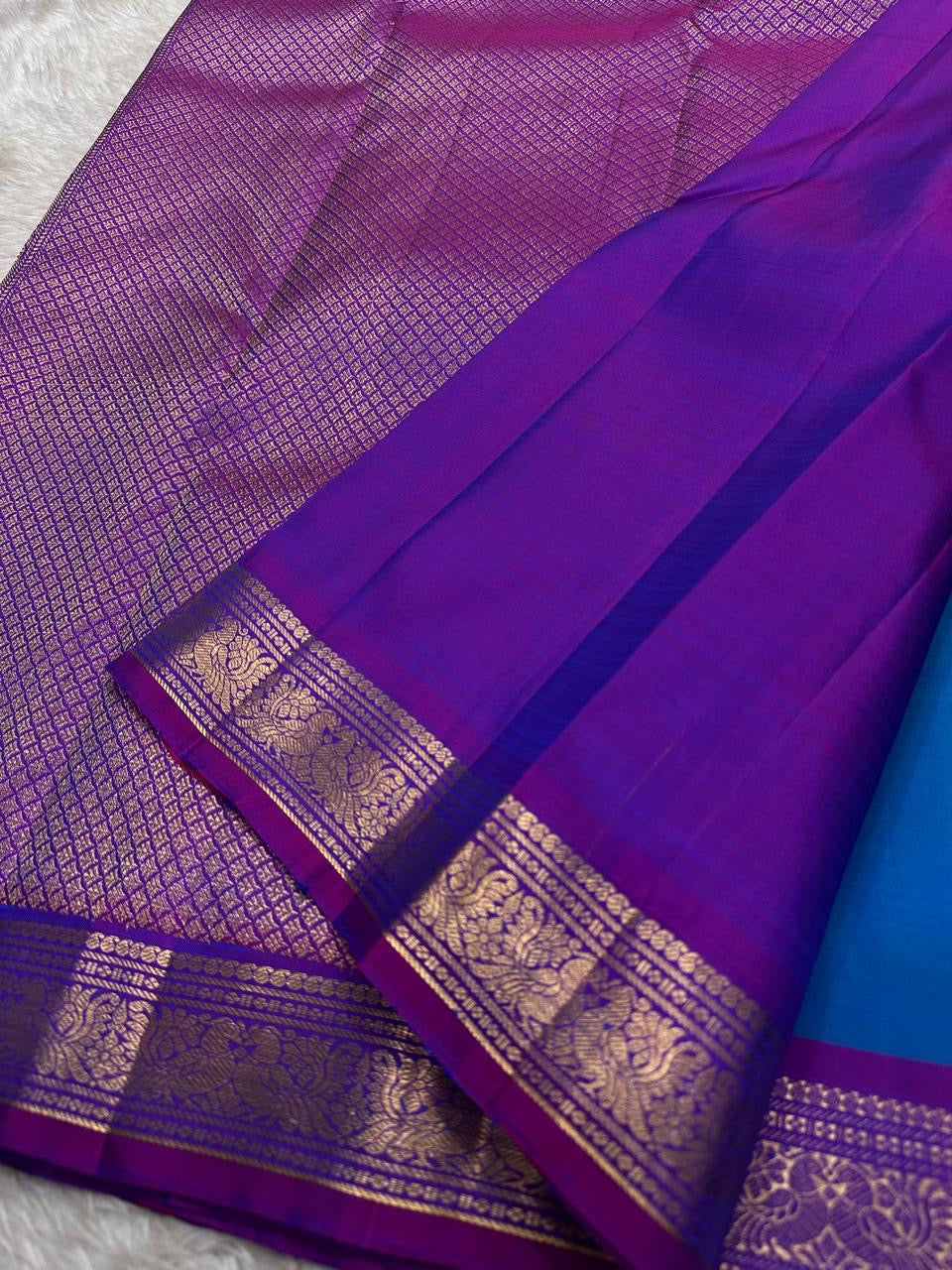 Close view of purple pallu with dense zari woven texture and a wide zari woven border panel on a Kanchipuram silk saree.