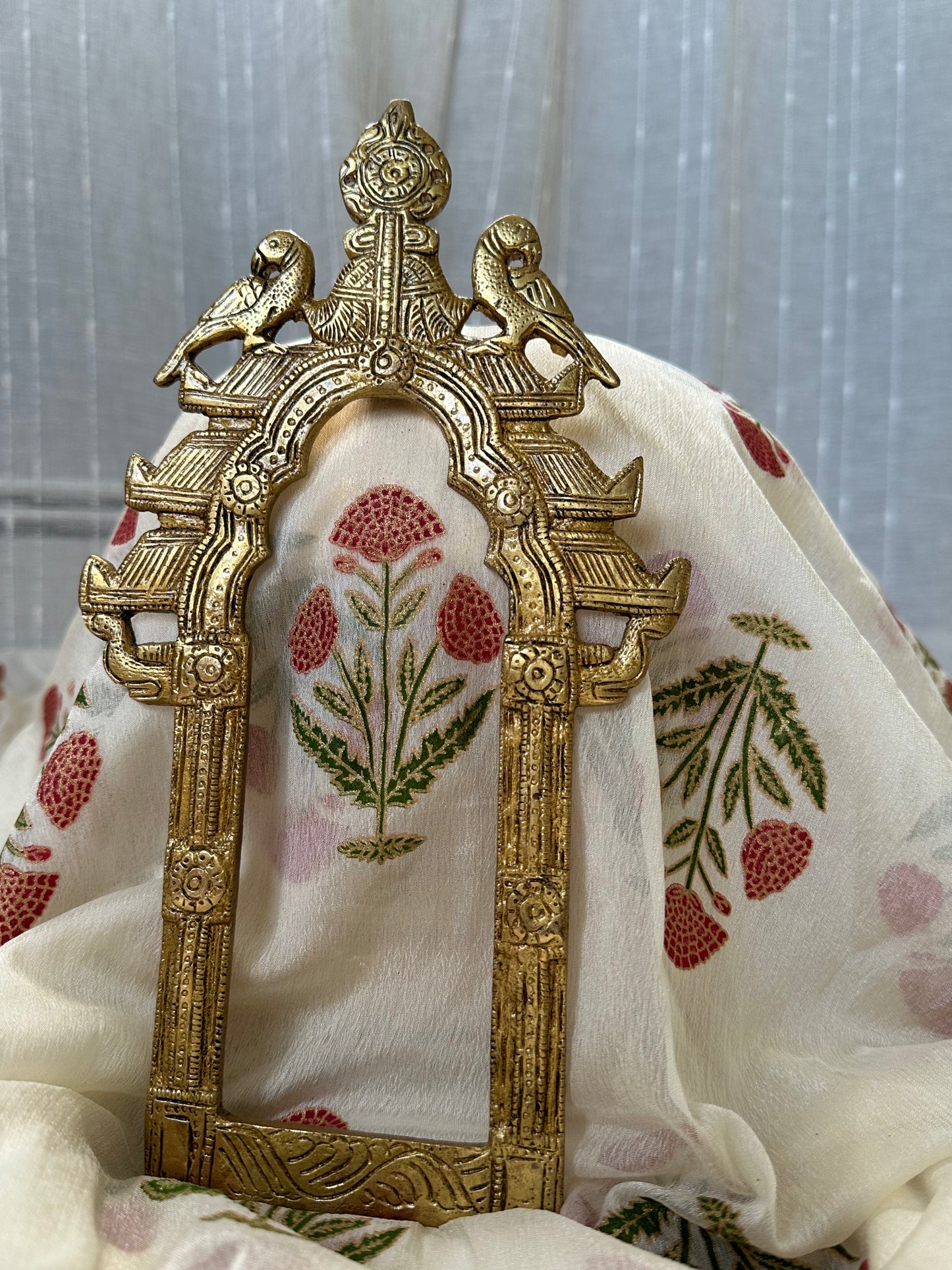 Decorative brass frame with floral embroidery on a fabric background