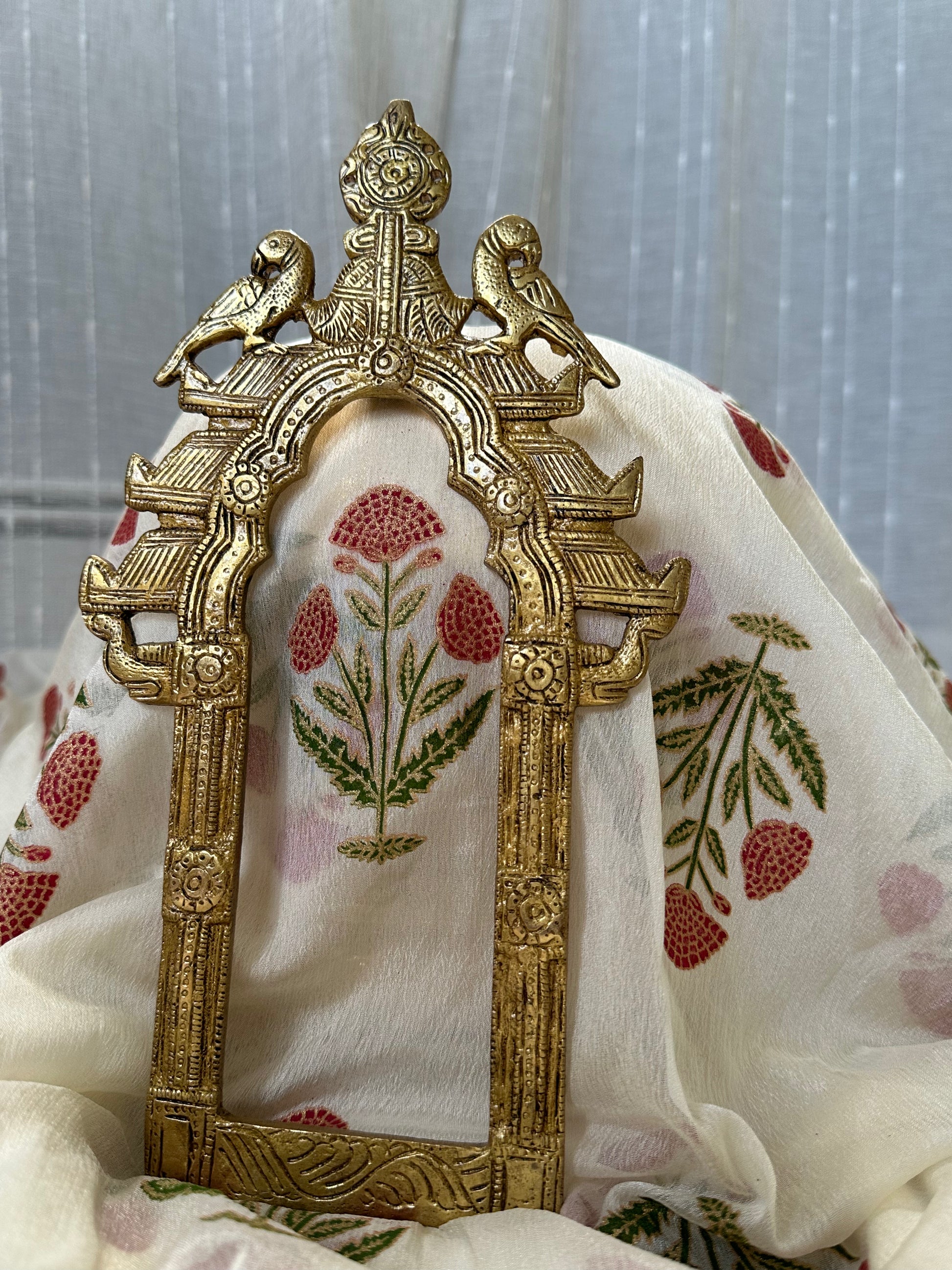 Decorative brass frame with floral embroidery on a fabric background