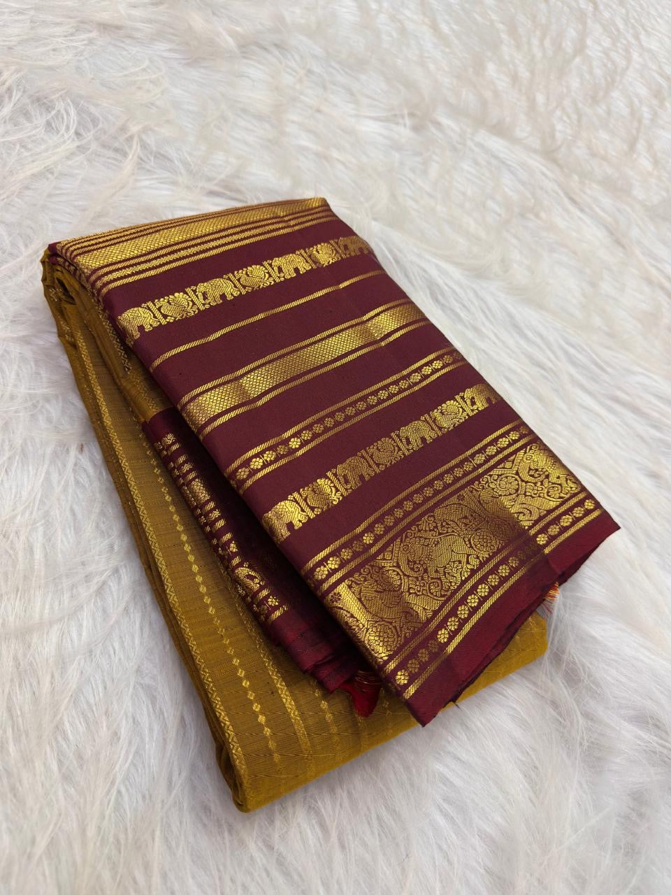 Arakku maroon Varisaipet border with gold zari bands, floral medallions and elephant figures on a turmeric yellow Kanjeevaram saree