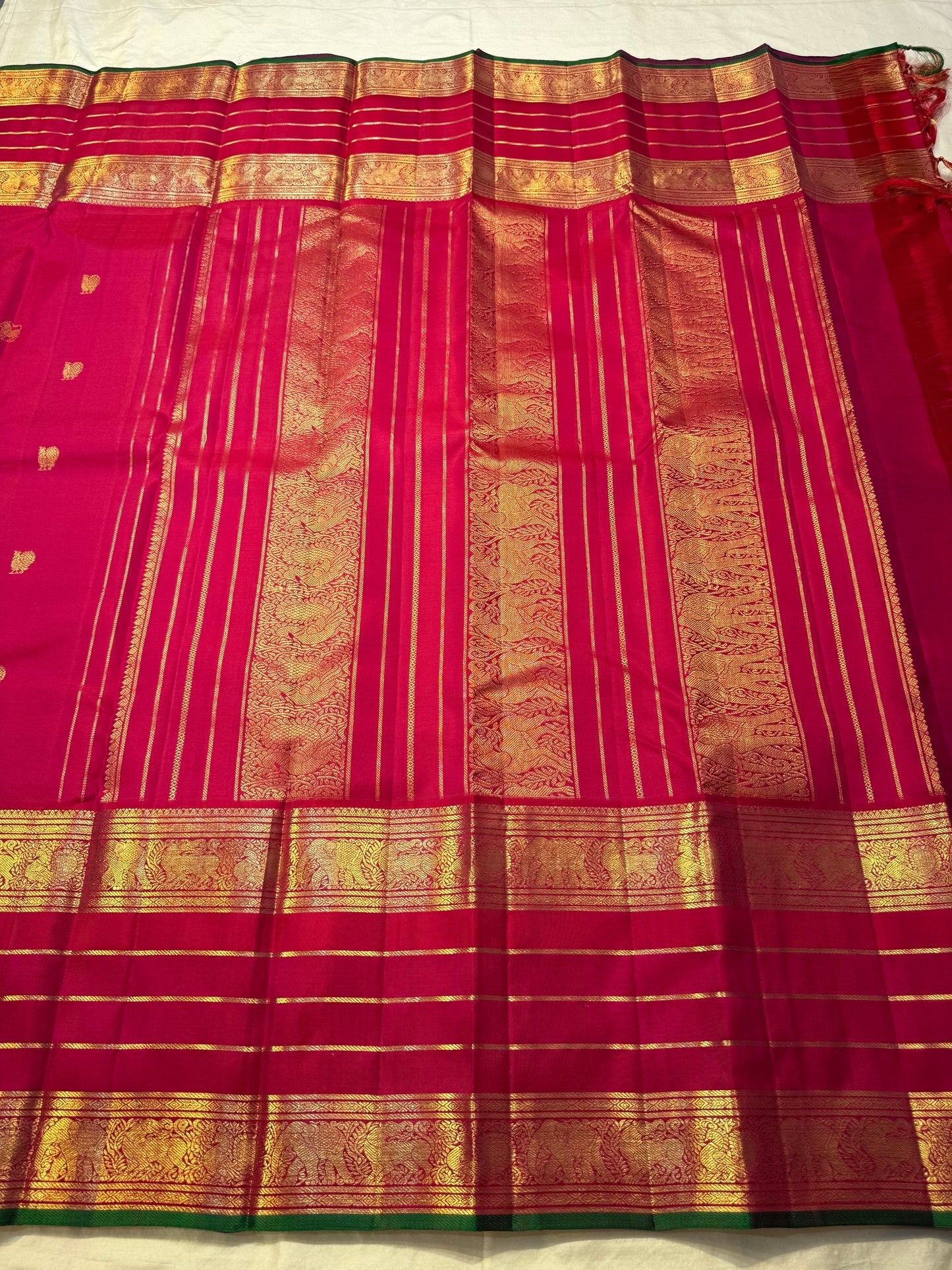 Ruby pink Kancheepuram silk saree with traditional zari detailing.