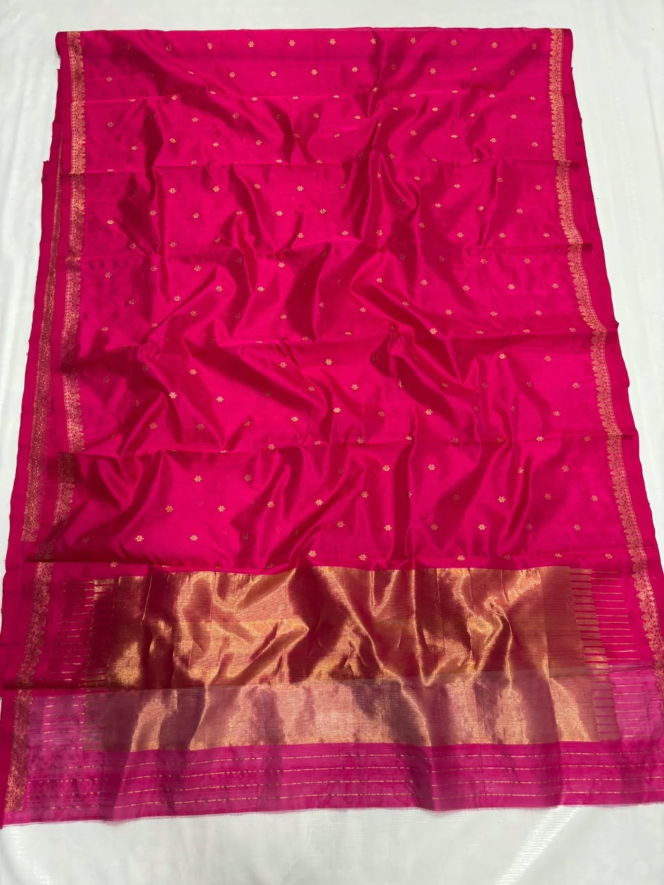Delicate ornamental gold-toned border on rani-pink saree