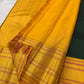 Repeated gold zari and silk-thread bands within the vivid yellow contrast border