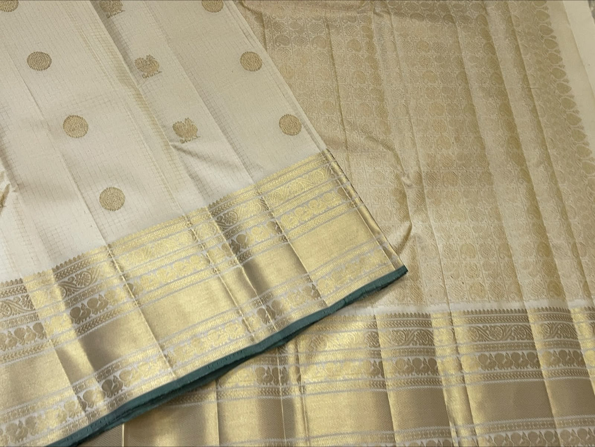 Warm ivory pure silk Kanchipuram saree showing fine gold zari kattam checks and petite Kili bird motifs